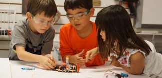 three students collaborate on a tinkering challenge