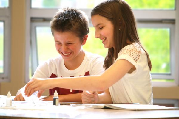 two kids at a desk smiling Thumbnail